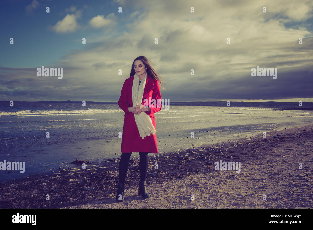 Donna in giacca rossa su una spiaggia. Foto Stock