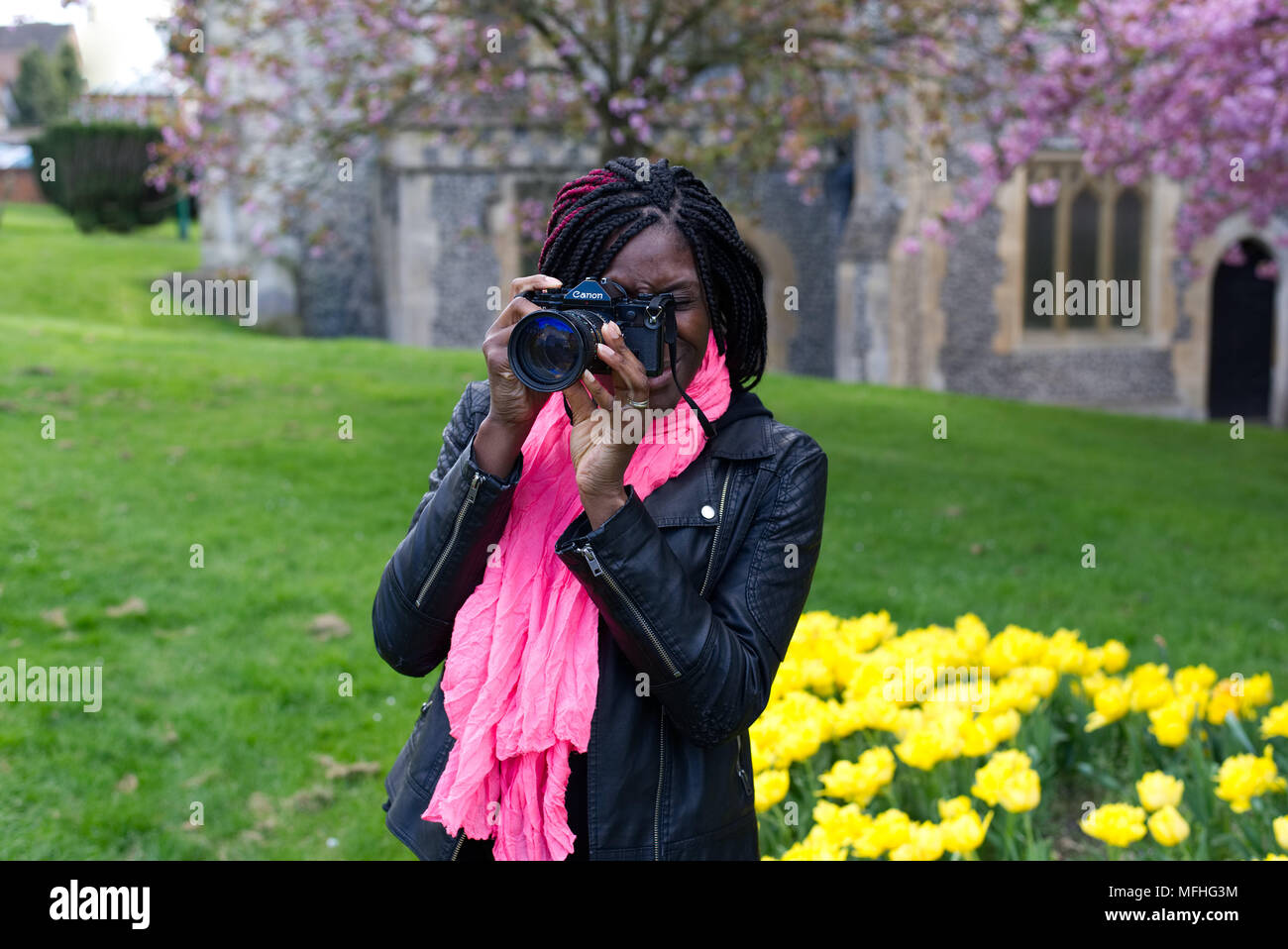 Signora nero utilizzando una Canon A-1 telecamera cinematografica nella motivazione della chiesa di Santa Maria in Hemel Hempstead's Old Town Foto Stock