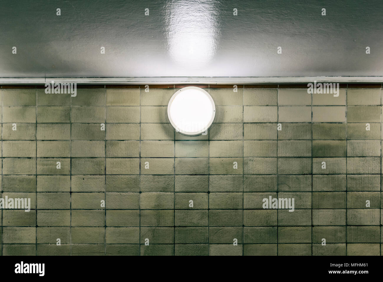 Close-up di un giro di luce sulla parete piastrellata del sottopasso della metropolitana Foto Stock