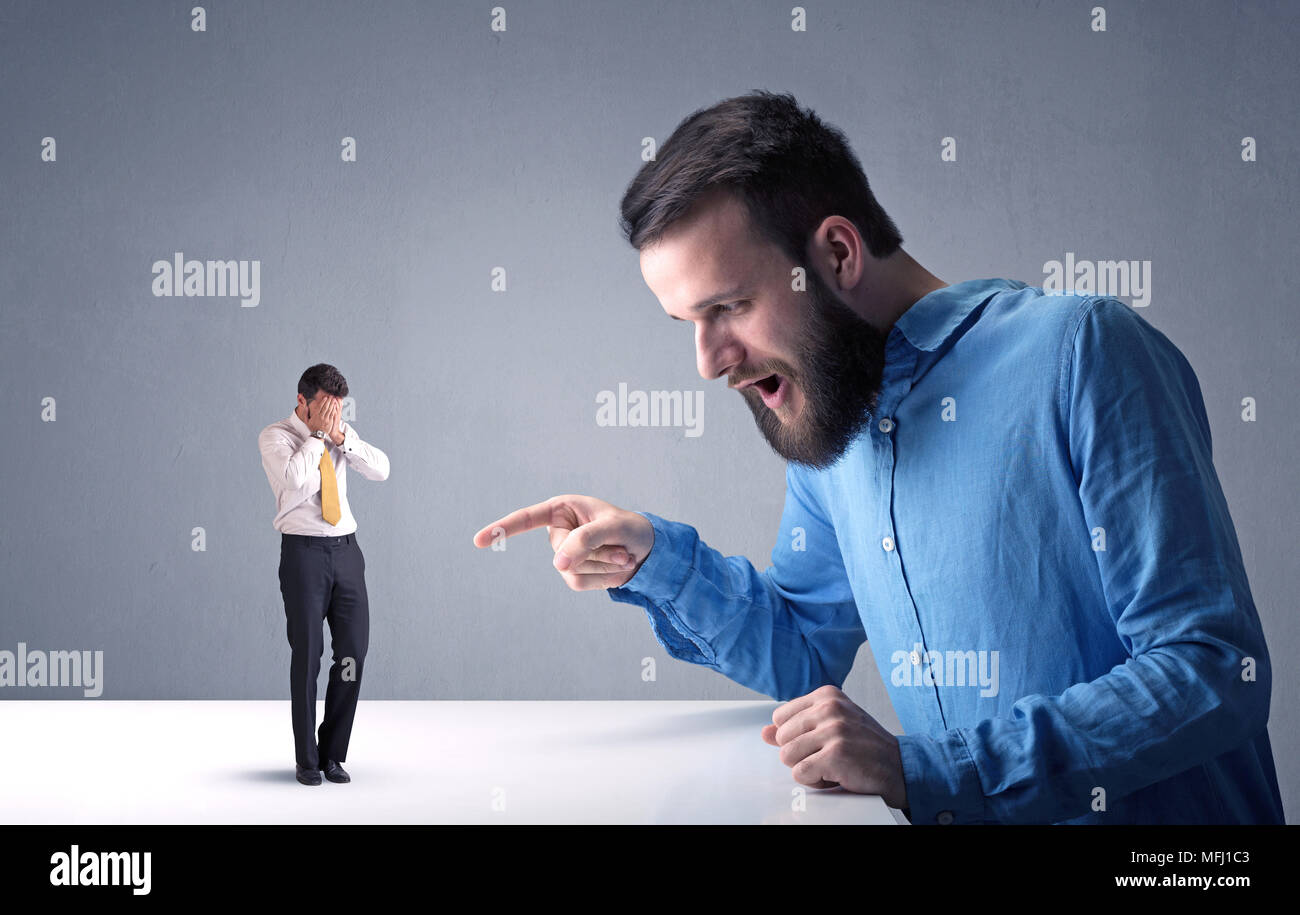 Giovane imprenditore professionale essendo arrabbiato con un altro imprenditore in miniatura Foto Stock