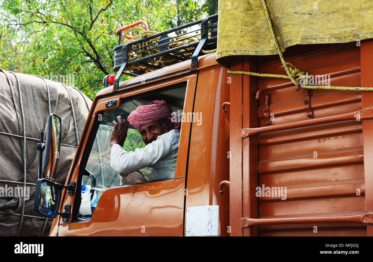Indian camionista dando una onda amichevole dal passaggio di un treno di trasportatore, India Foto Stock