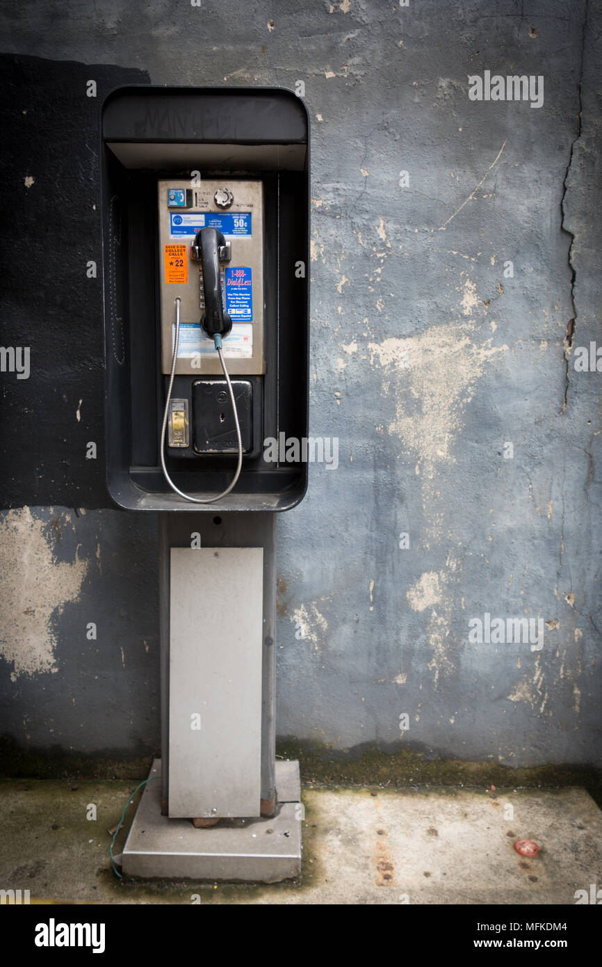 Un telefono a pagamento di fronte ad una parete blu con peeling paint Foto Stock