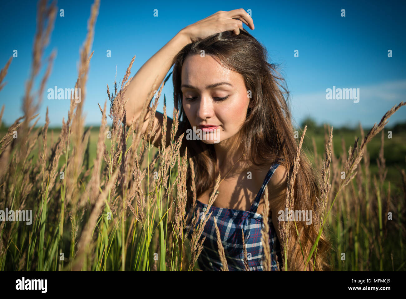 Giovane donna in piedi su un campo di erba in giornata estiva sulla natura dello sfondo. Bella ragazza godendo di estate. Foto Stock