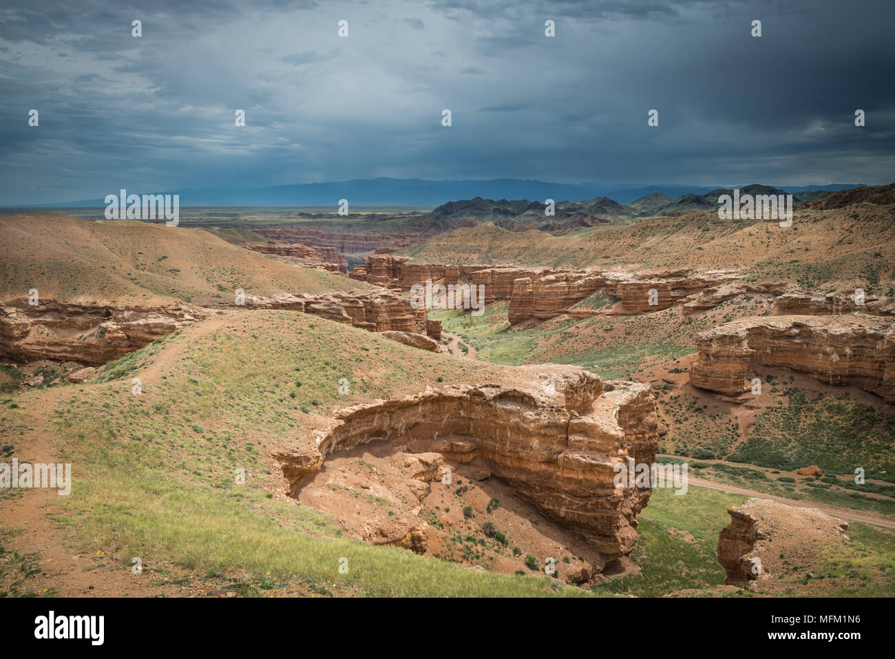 Paesaggio panoramico con vista sul canyon e le montagne lontano. Nuvoloso cielo drammatico. Foto Stock