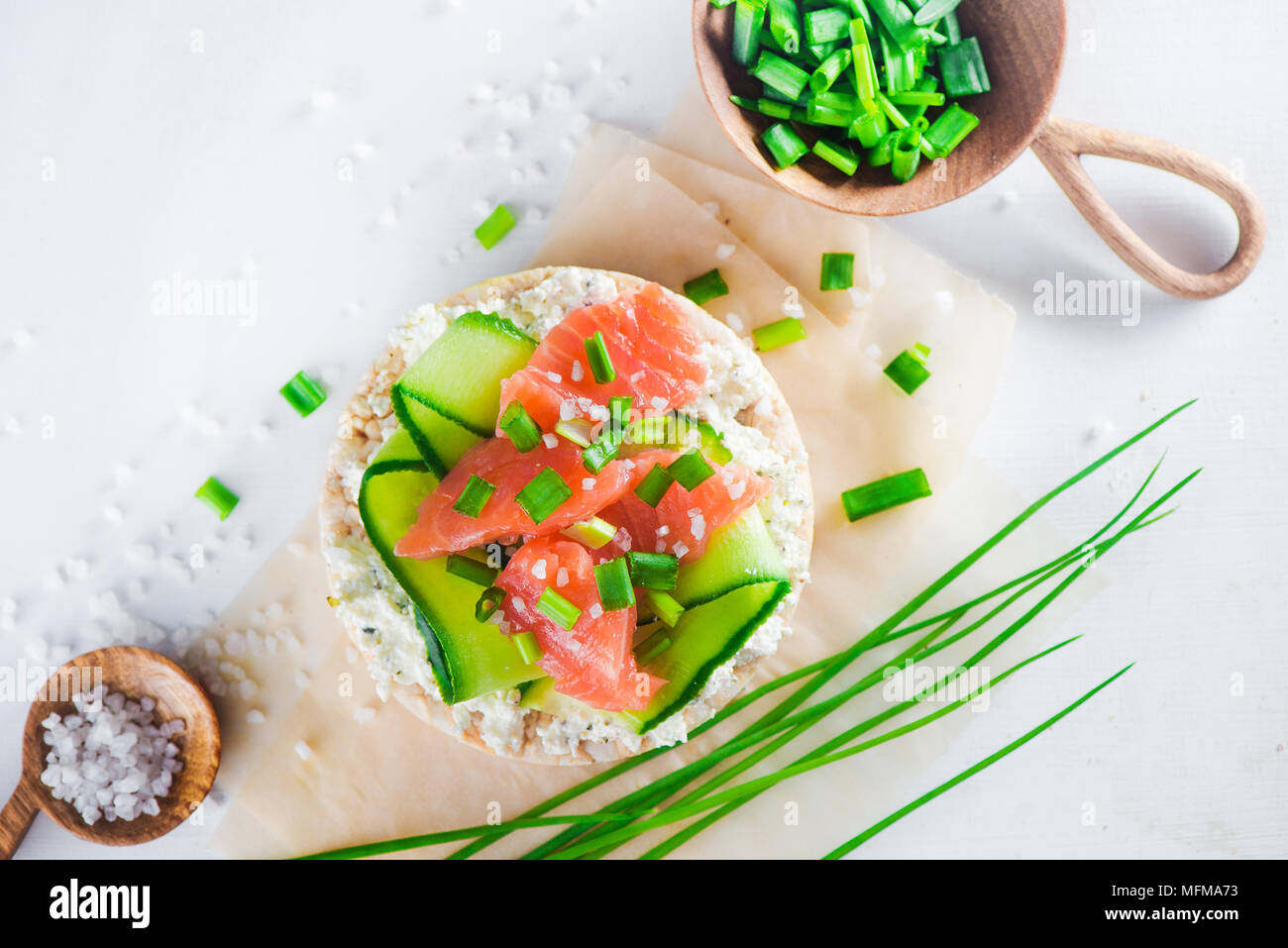 Pane croccante snack sani con salmone, ricotta, strisce di cetriolo, scalogno e sale marino. Colazione semplice concetto di close-up con copia spazio. Foto Stock