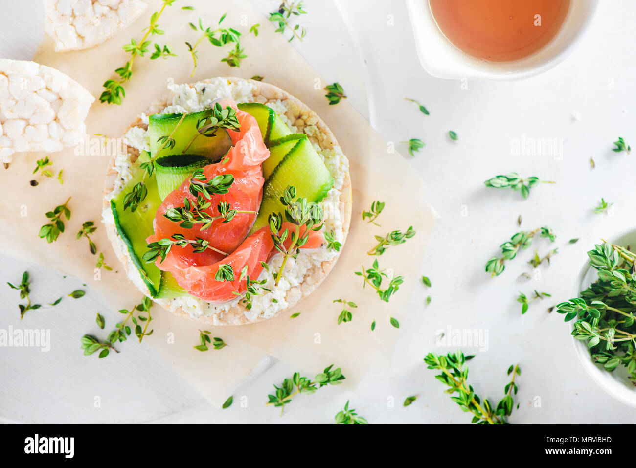 Pane croccante snack sani con salmone, ricotta, strisce di cetriolo, il timo e il pepe. Colazione semplice concetto di close-up con copia spazio. Foto Stock