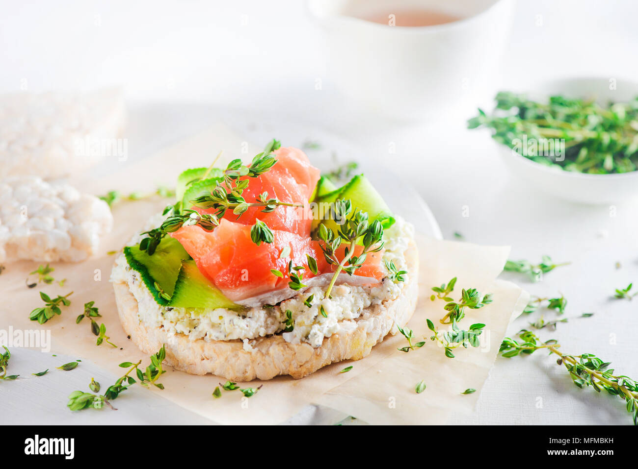 Pane croccante snack sani con salmone, ricotta, strisce di cetriolo, il timo e il pepe. Colazione semplice concetto di close-up con copia spazio. Foto Stock