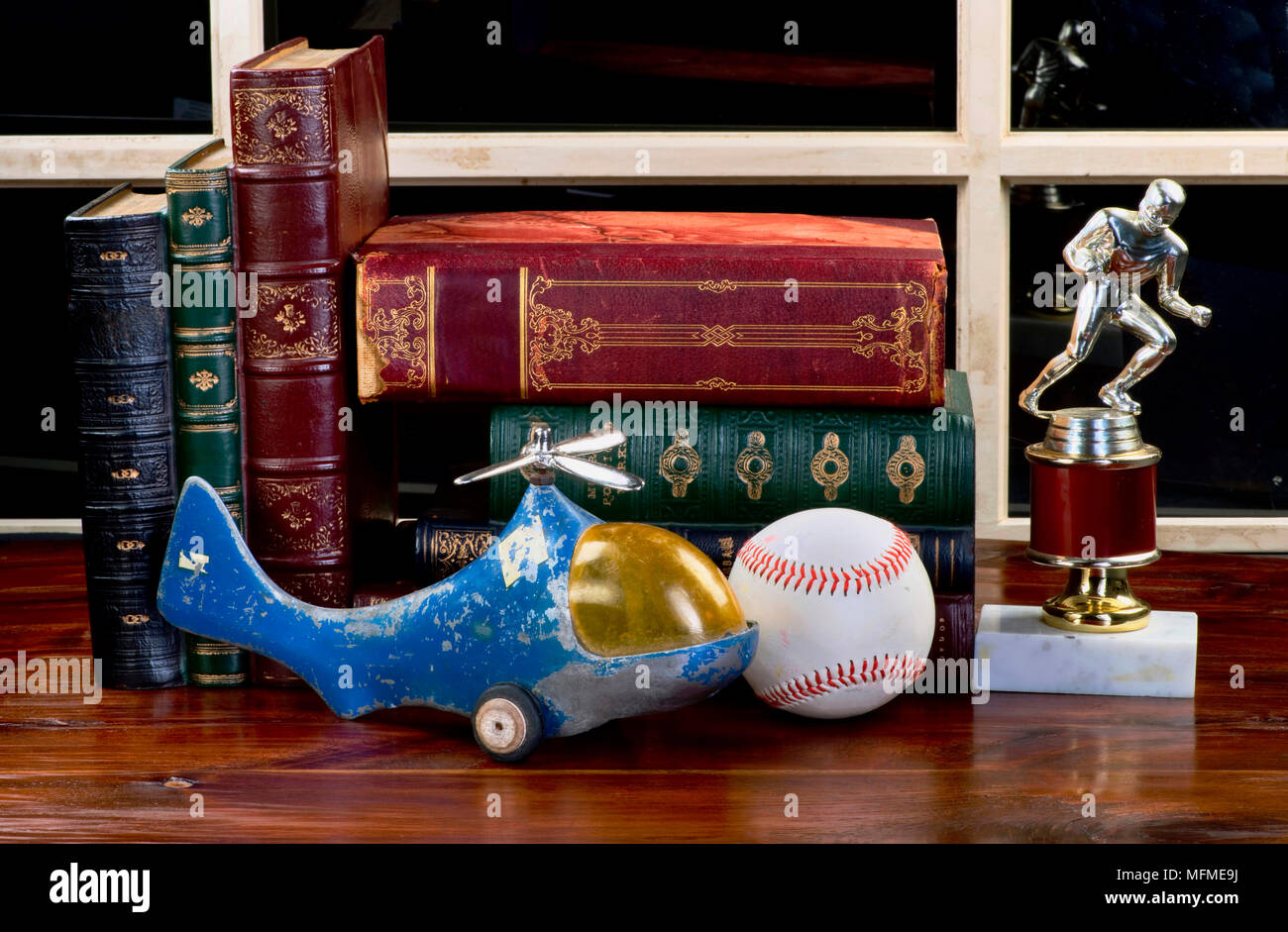 Vecchi giocattoli di infanzia,libri e ricordi sportivi sulla scrivania in legno. Foto Stock