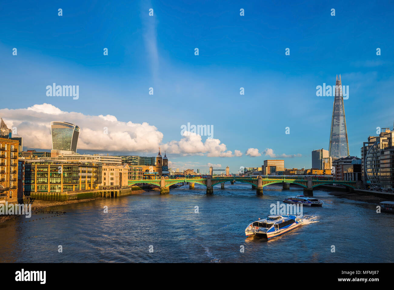 Londra, Inghilterra - imbarcazioni turistiche al tramonto sul fiume Tamigi con Southwark Bridge e il Tower Bridge e grattacieli in background Foto Stock