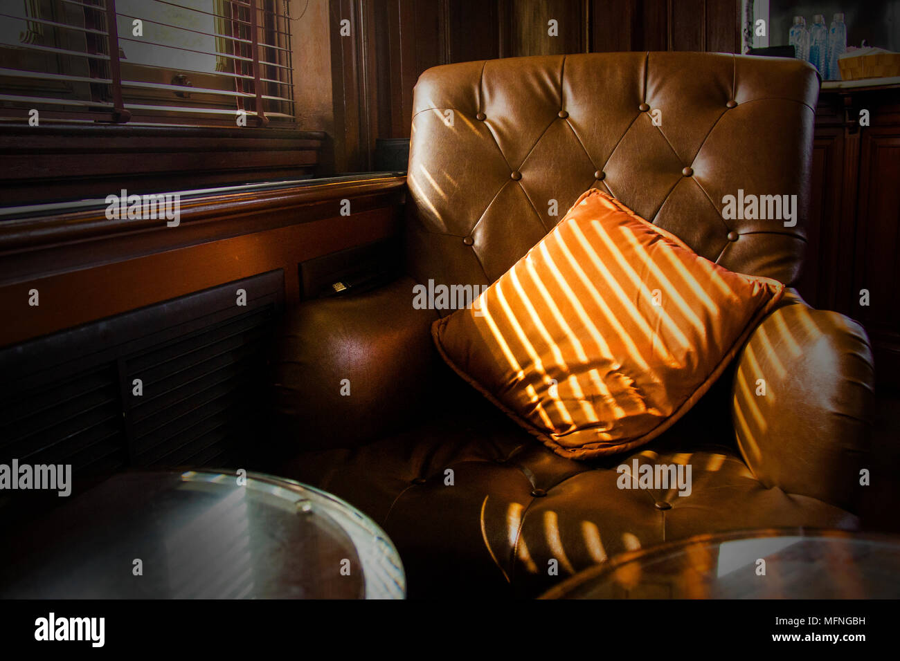 Divani in pelle marrone sedia vicino a finestra in camera oscura Foto Stock
