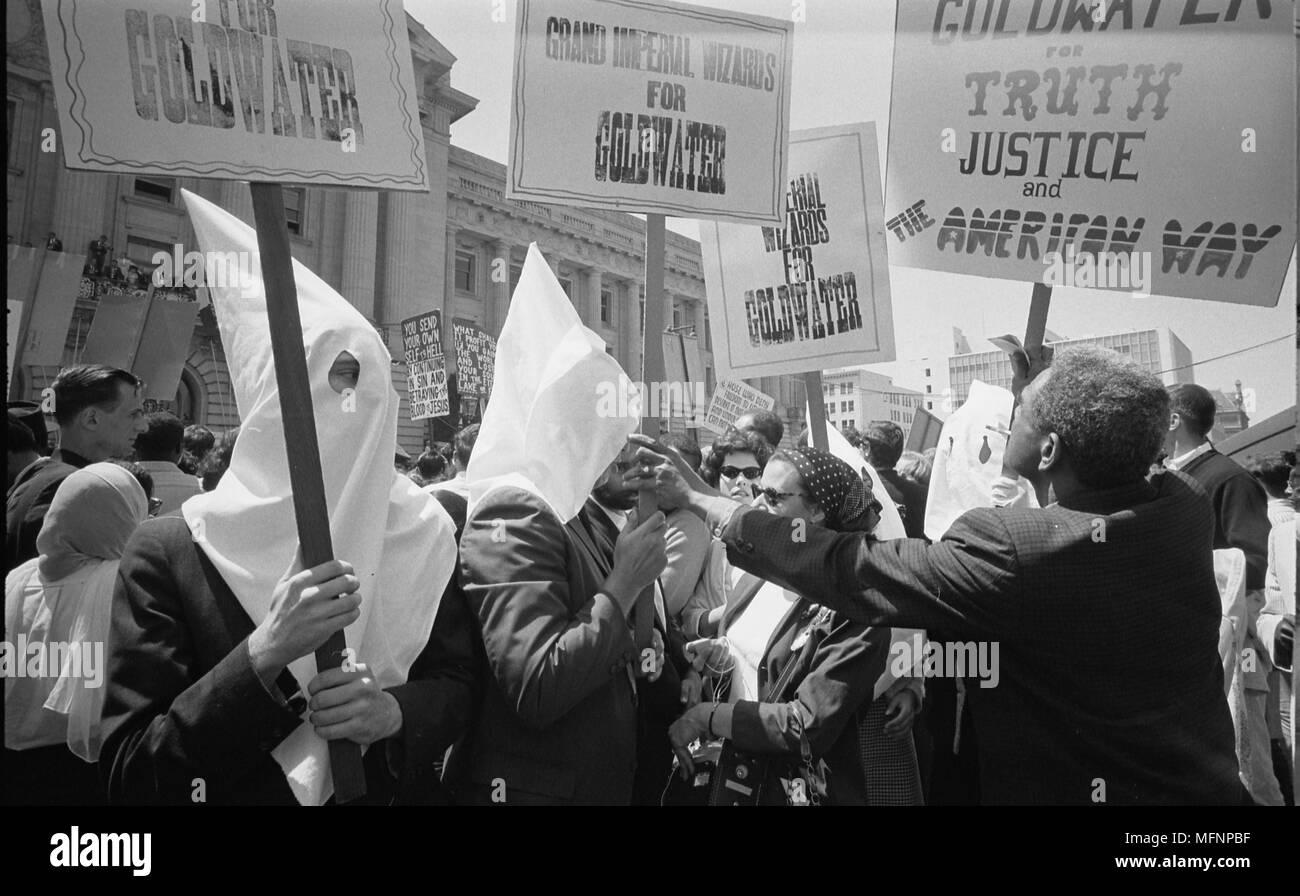 Membri del Ku Klux Klan il supporto di Barry Goldwater la campagna per la nomina presidenziale alla Convention Nazionale Repubblicana, San Francisco, California, come un americano africano uomo segni spinge indietro: 12 luglio 1964. Fotografo: Warren Leffler K. Foto Stock