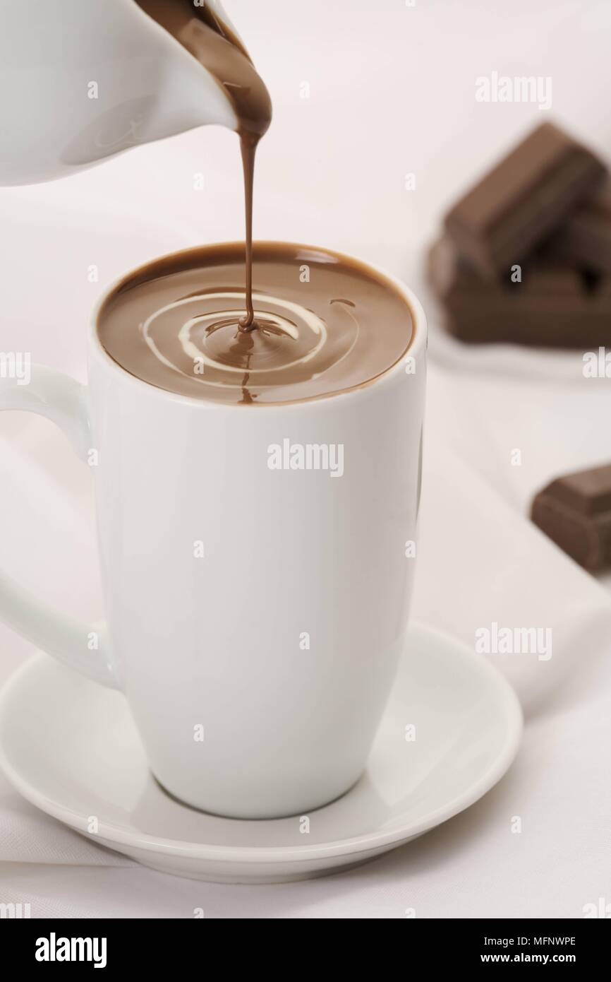 La bevanda al cioccolato di essere versata in porcellana bianca cup. Cioccolato in background. Studio shot. Ref: CRB538 103609 0007 credito obbligatoria: Marti Foto Stock