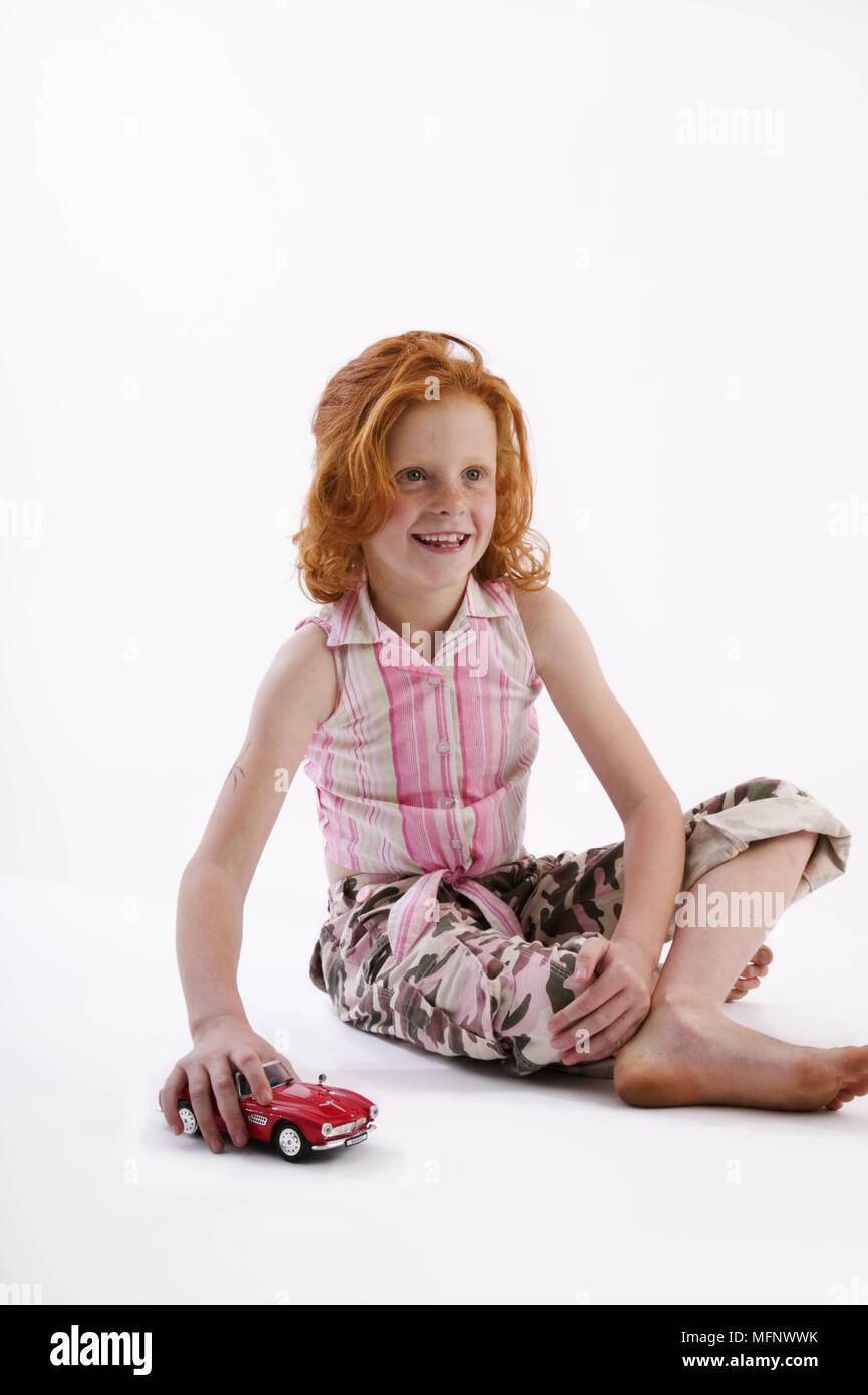 Ragazza con i capelli rossi e le lentiggini, età 7, giocando con una macchina giocattolo. Modello rilasciato. Studio shot. Ref: CRB538 103609 0038 OBBLIGATORIO DI CREDITO: M Foto Stock