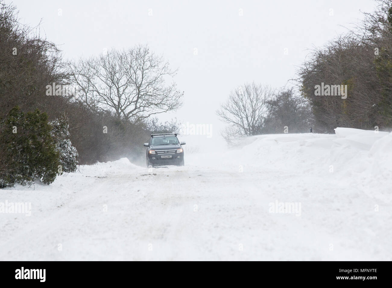 Gli automobilisti la bordatura attraverso le derive di neve e vento forte come il loro viaggio sulla strada Gloucestrer outsiode Cirencester NEL REGNO UNITO. Foto Stock
