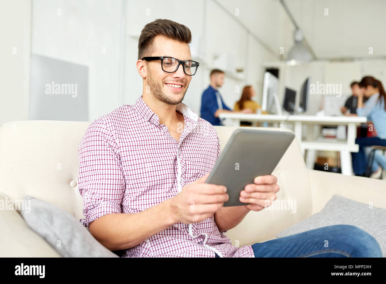 Uomo in bicchieri con tablet pc lavorando in ufficio Foto Stock