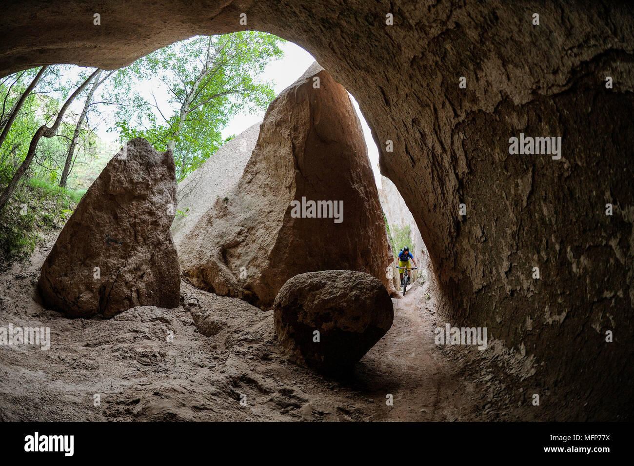 Un uomo corse in mountain bike attraverso le grotte e canyon di Cappadocia in Turchia. Foto Stock