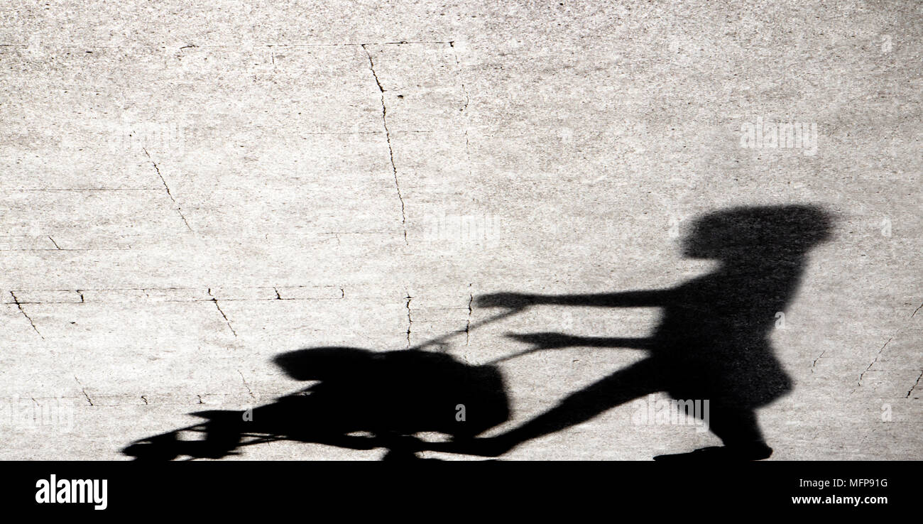 Ombra silhouette di una giovane donna di spingere un passeggino sul marciapiede della città in bianco e nero Foto Stock