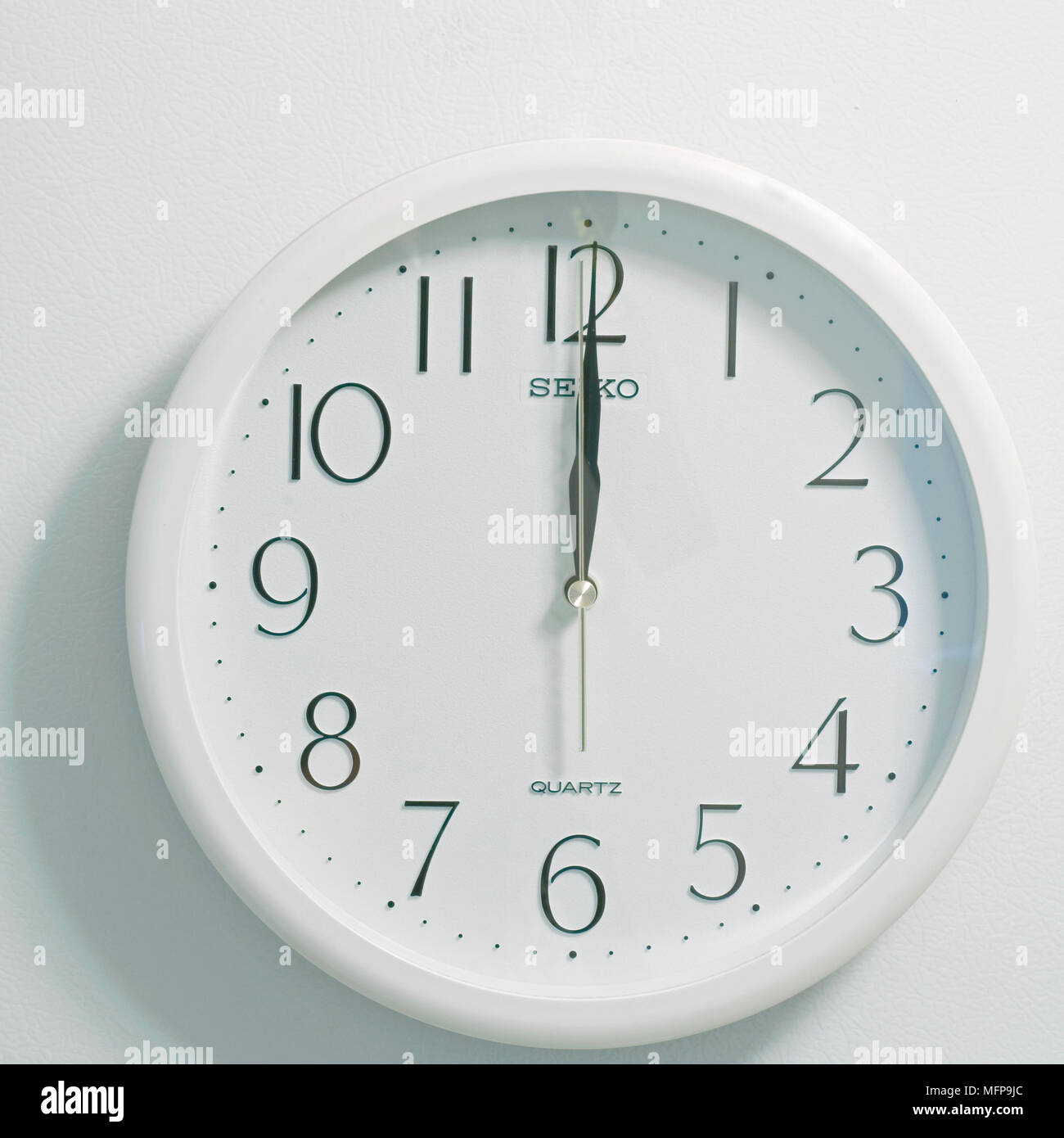 Primo piano della faccia del moderno stile orologio mostra bianco rotondo e quadrante nero al momento dodici ore di mezzogiorno o mezzanotte su sfondo bianco Foto Stock