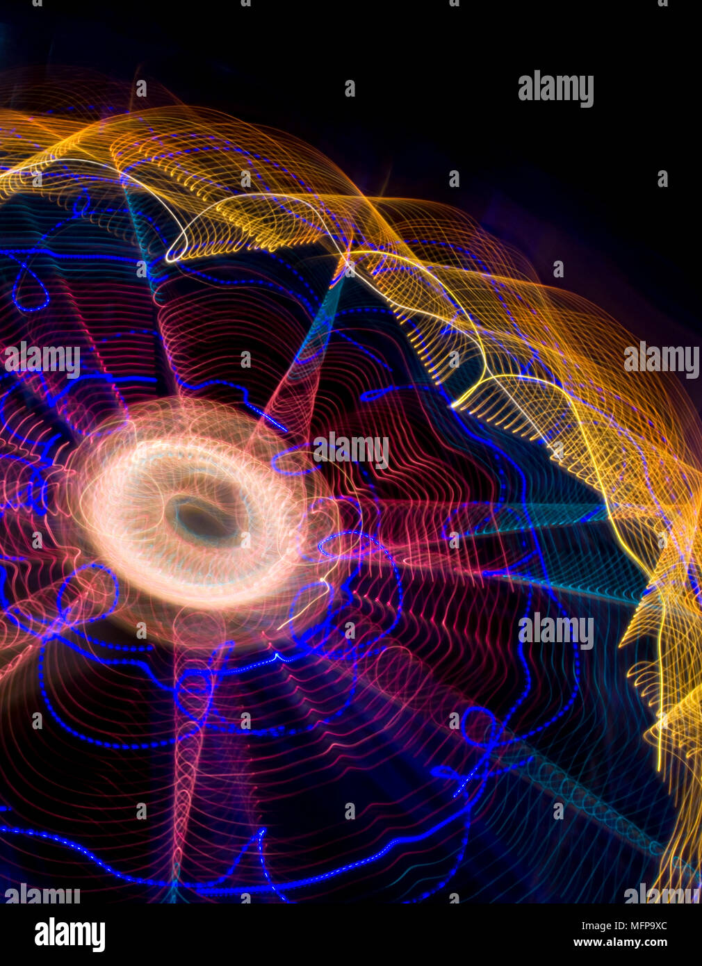 Un energico abstract delle luci di una fiera ruota panoramica Ferris di notte che mostra la filatura anelli a raggi di luce e sentieri effetto creato con lo zoom Foto Stock