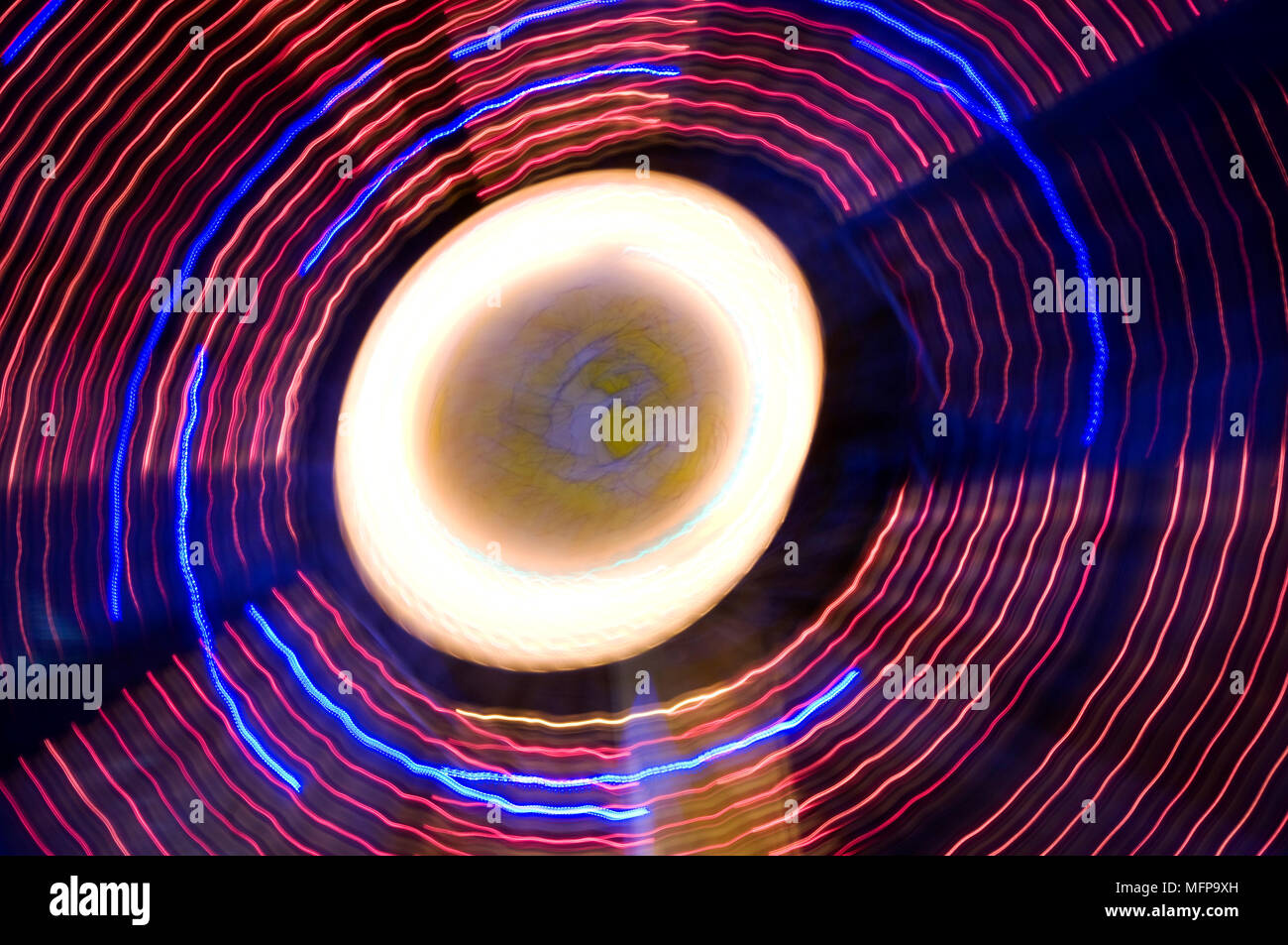 Un energico abstract delle luci di una fiera ruota panoramica Ferris di notte che mostra la Anelli di filatura ad una lunga esposizione. Foto Stock