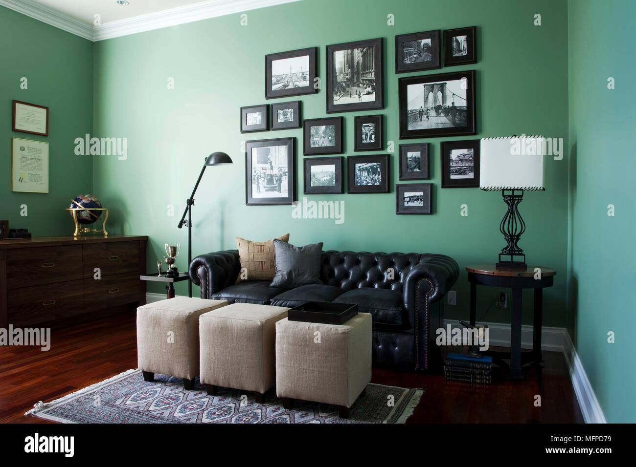 La disposizione delle fotografie al di sopra del cuoio divano Chesterfield in verde studio, New York, Stati Uniti d'America Foto Stock
