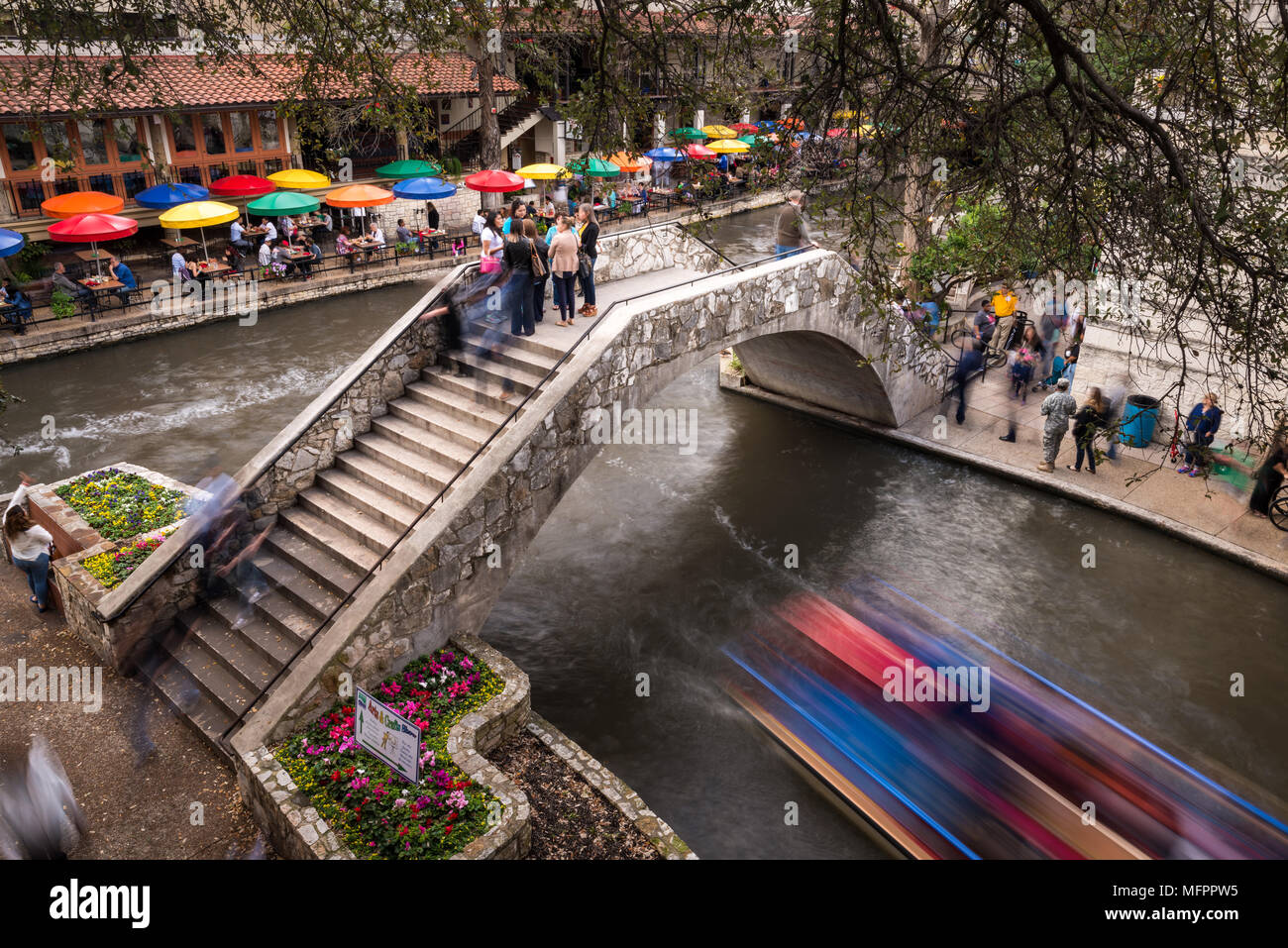 Parte del San Antonio Riverwalk con le persone camminare su un ponte sul fiume e gli edifici e i ristoranti in primavera, Texas, Stati Uniti d'America Foto Stock
