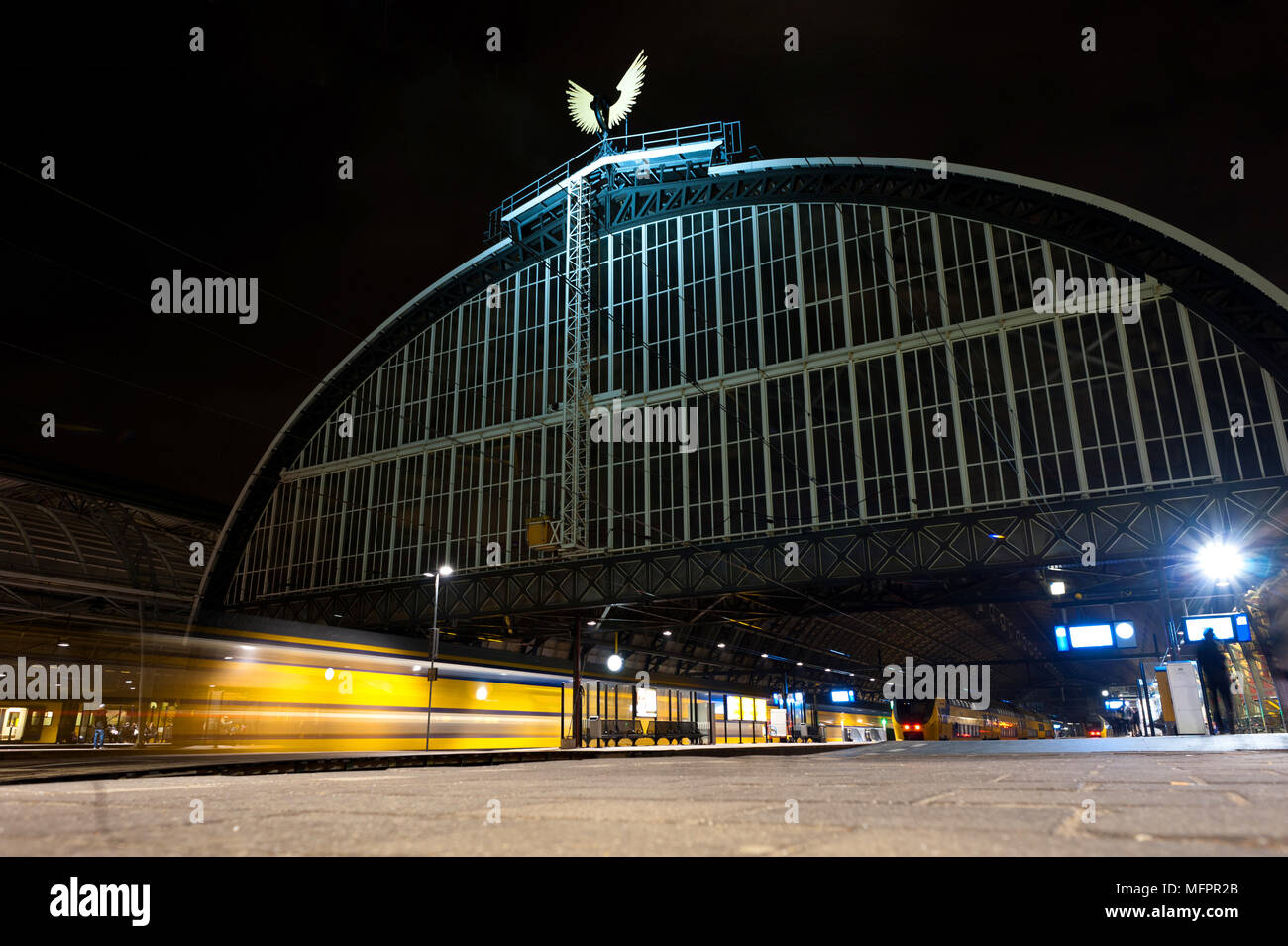 La stazione ferroviaria centrale di Amsterdam di notte. Treno arriva alla stazione. Esposizione lunga notte foto. Foto Stock