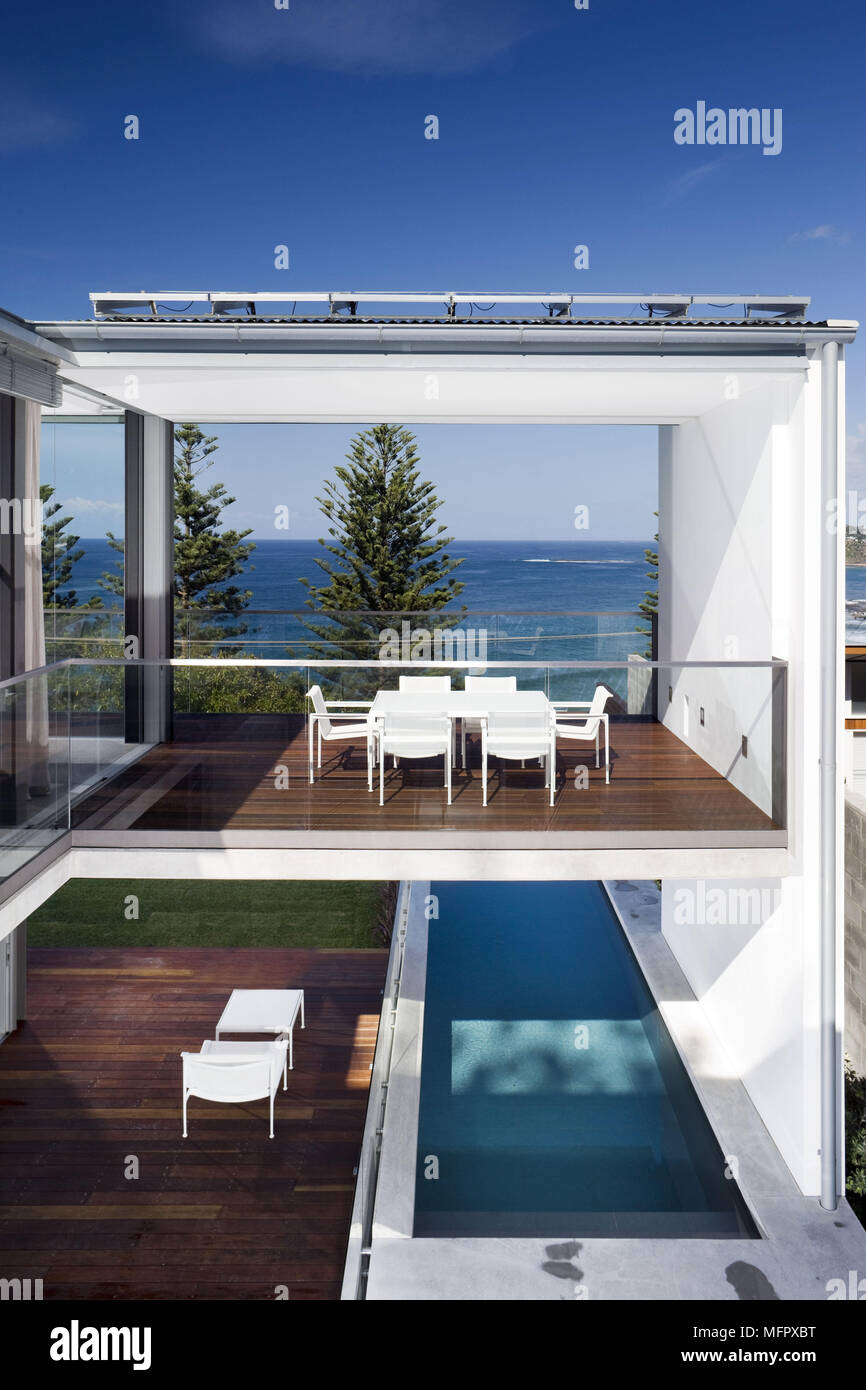 Tavolo e sedie sul patio arredato al di sopra della piscina di casa moderna Foto Stock