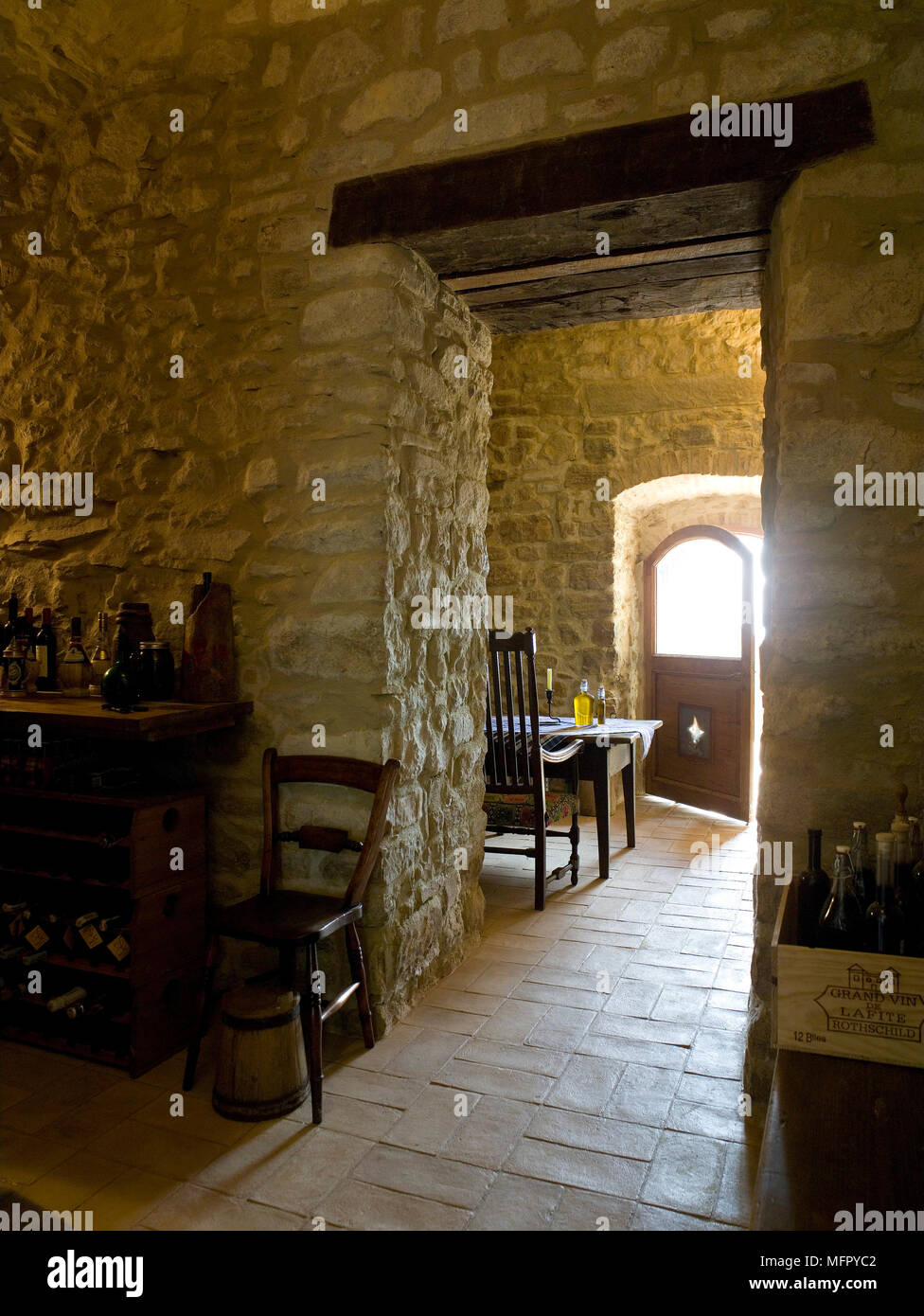 Vista attraverso il portale in pietra rustica sala con tavolo e sedie Foto Stock