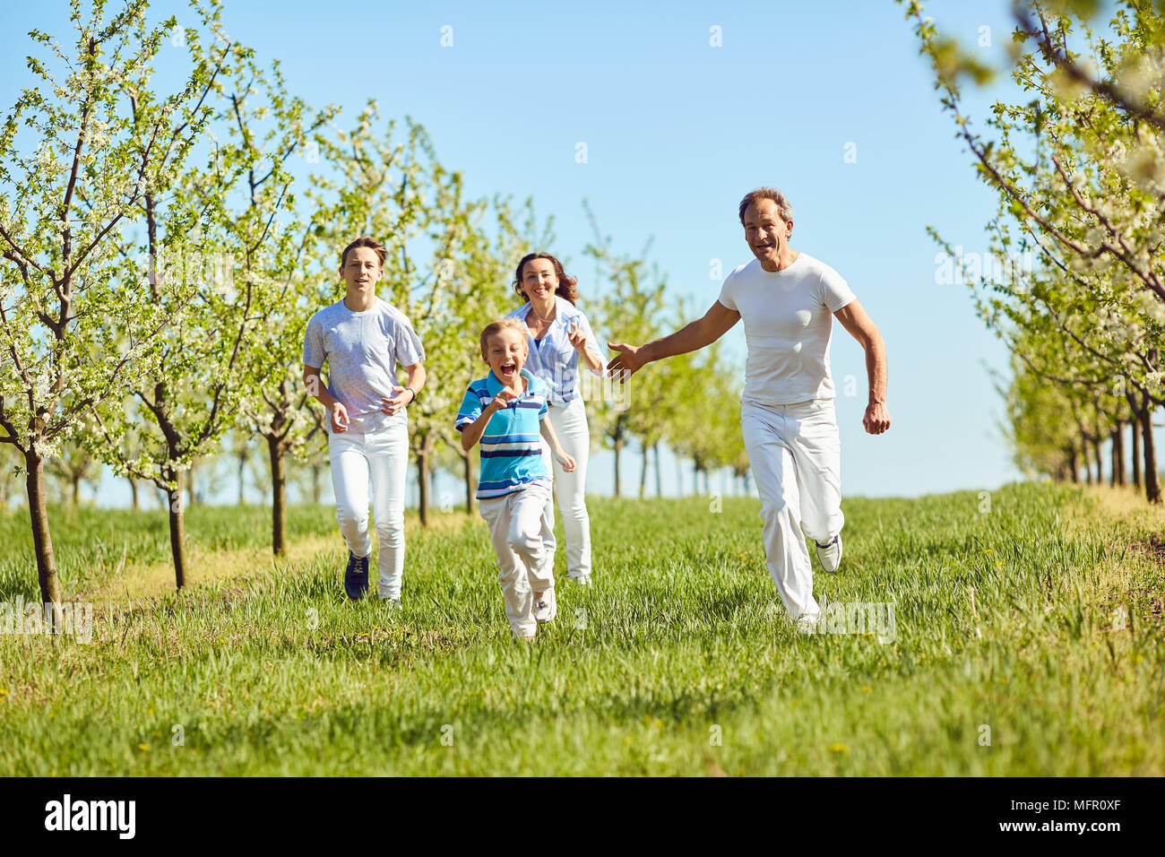 La famiglia felice avendo divertimento passeggiate nel giardino in primavera, d'estate. Foto Stock