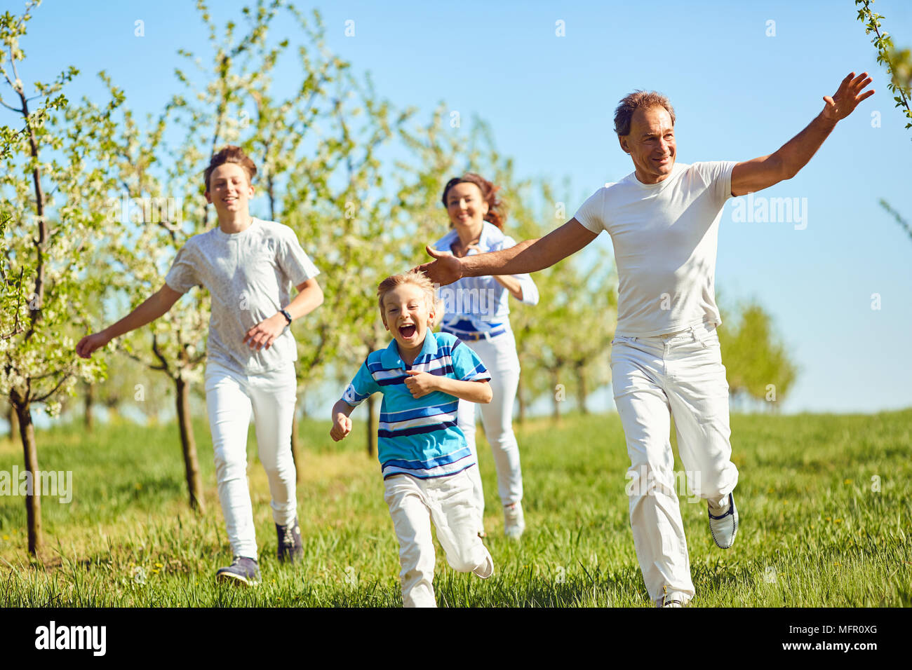 La famiglia felice avendo divertimento passeggiate nel giardino in primavera, d'estate. Foto Stock