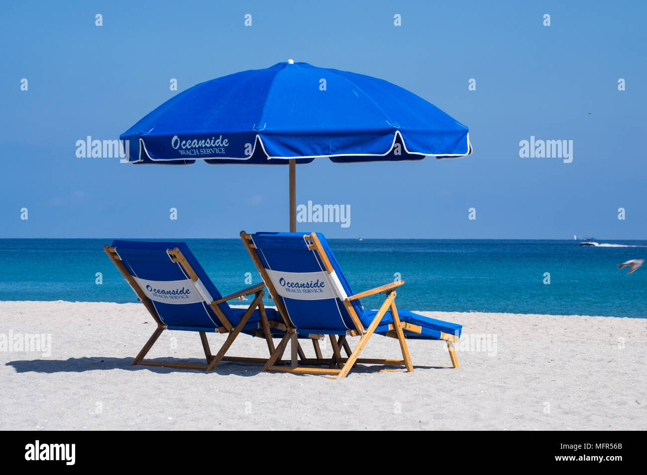 Rilassatevi nel Delray Beach Florida sulla sabbia, sotto un ombrellone con sdraio guardando il mare blu profondo. Foto Stock