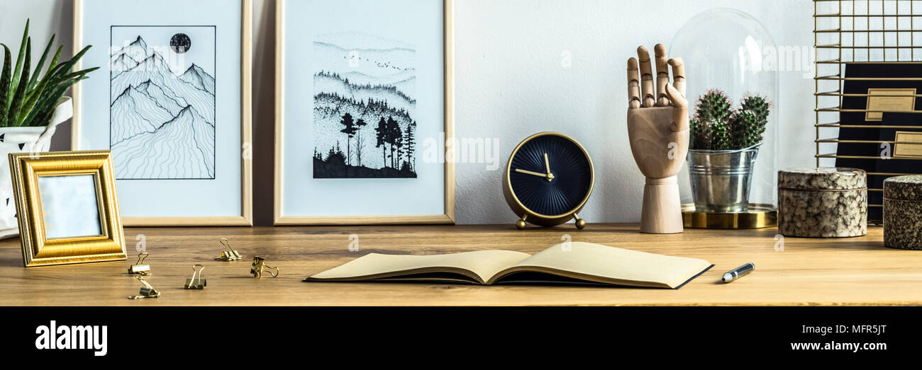 Due semplici poster collocato su una scrivania di legno con i notebook, nero e oro orologio e cactus Foto Stock