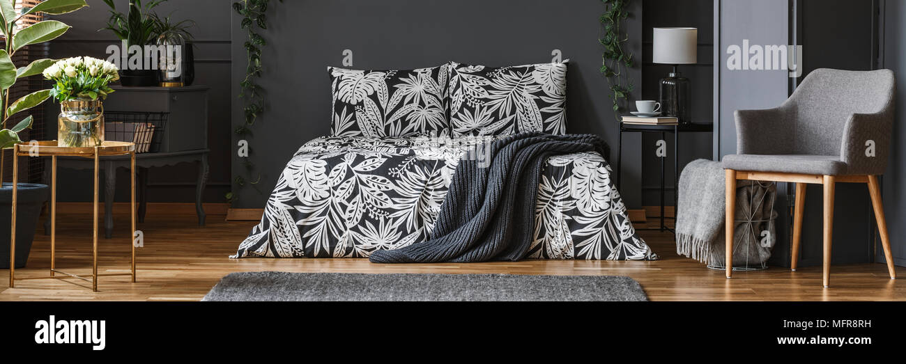 Panorama di scuro, elegante camera da letto interni con coperta grigio  sdraiato sul letto con copriletti floreali Foto stock - Alamy