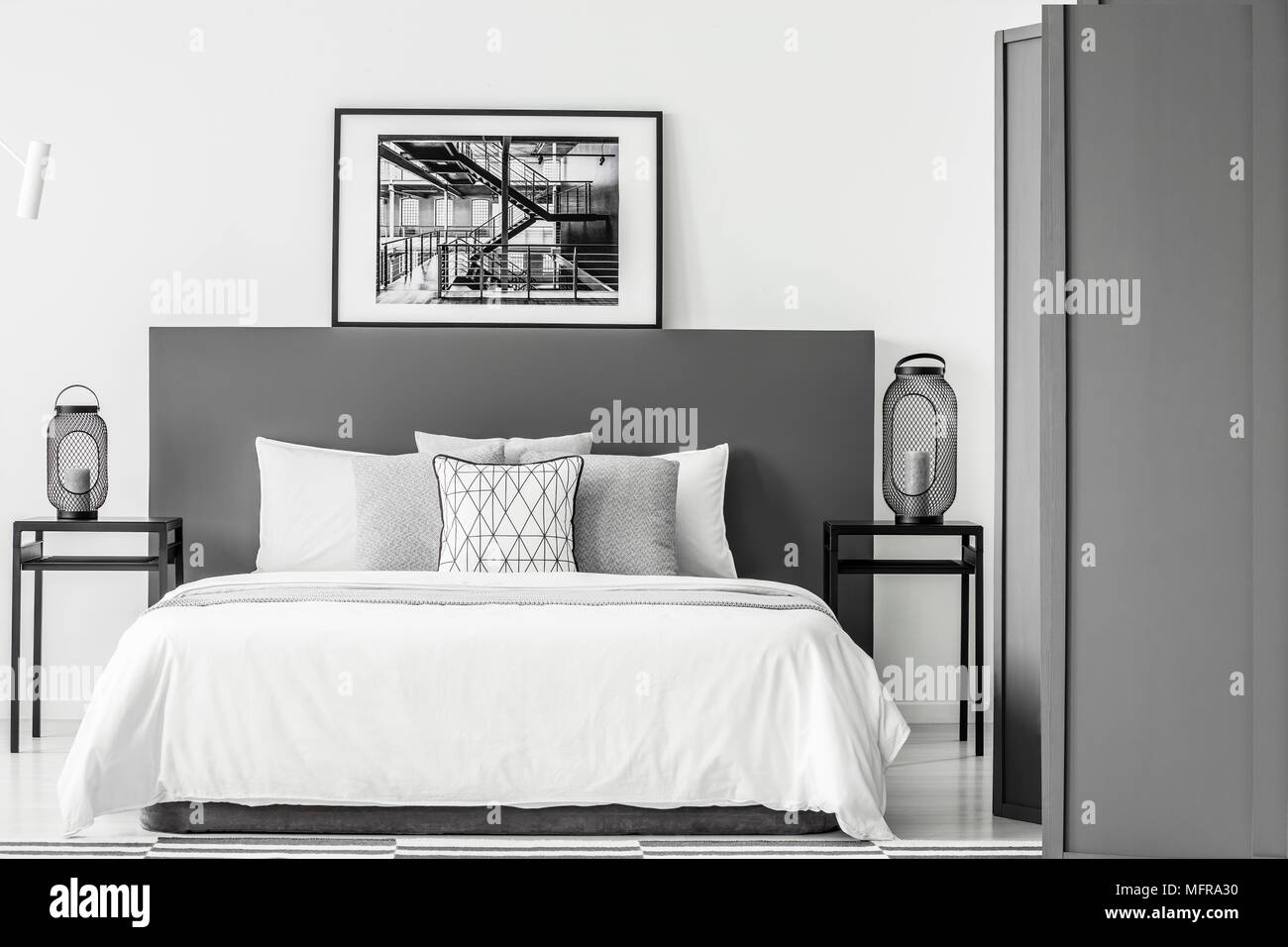 In bianco e nero poster sulla testata del letto in camera da letto interno con lanterne su tabelle Foto Stock
