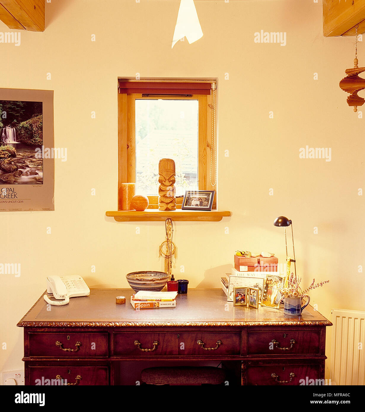 Piccola finestra in legno sopra il cassetto unità nel paese camera da letto pareti neutre foto incorniciate ornamenti di telefono a parete il raccordo luce di bordo del soffitto travi Foto Stock