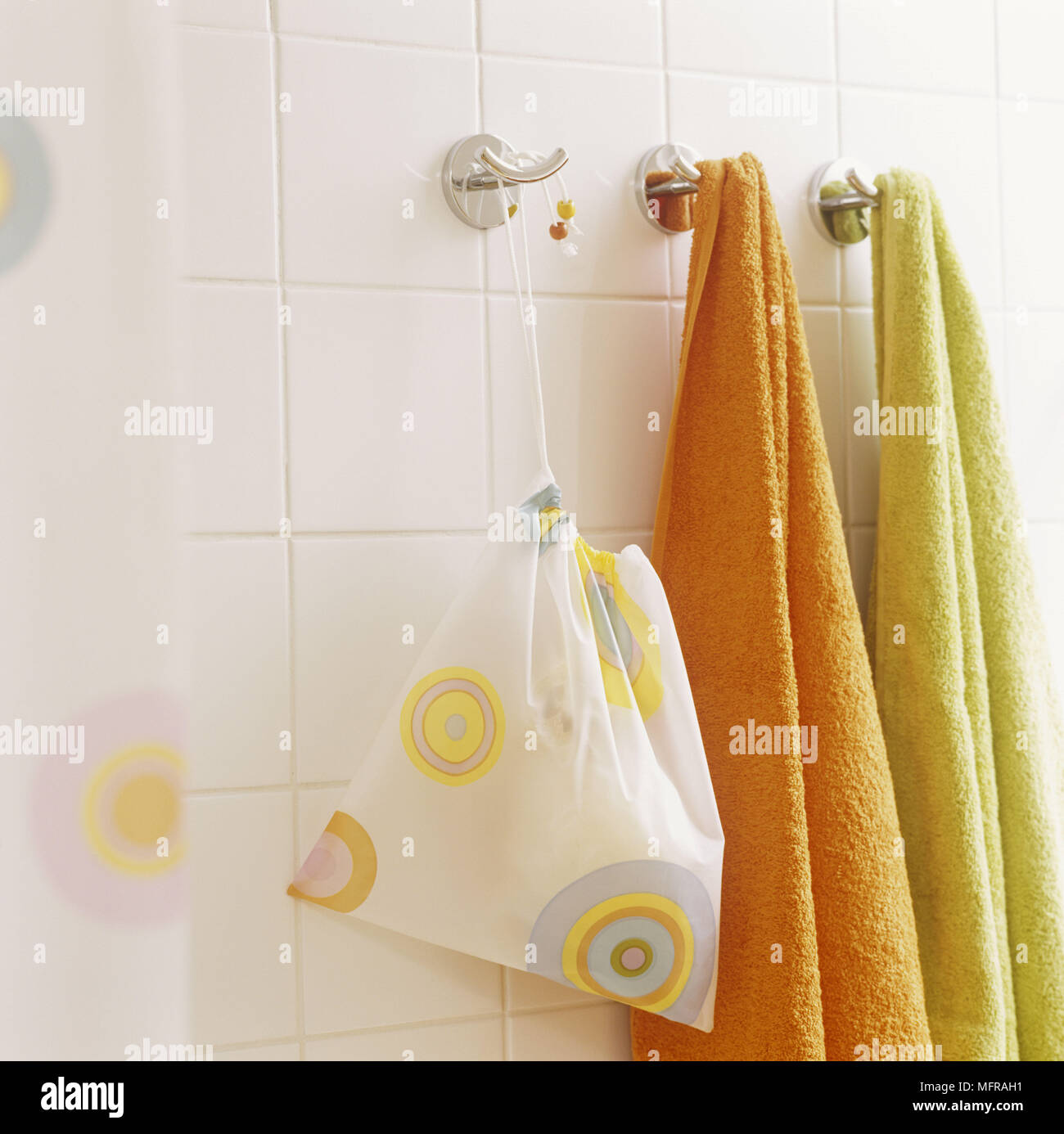 Accessori per il bagno e asciugamani appesi a ganci di acciaio su bianco  parete piastrellata Foto stock - Alamy