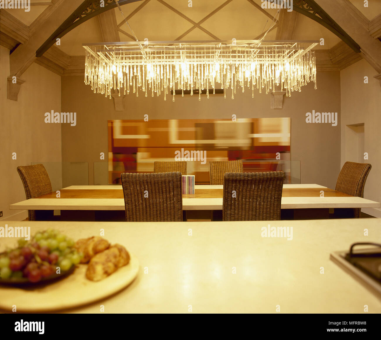Moderna area da pranzo con tavolo da pranzo e sedie di vimini, il soffitto a travi e un lampadario decorativa. Foto Stock