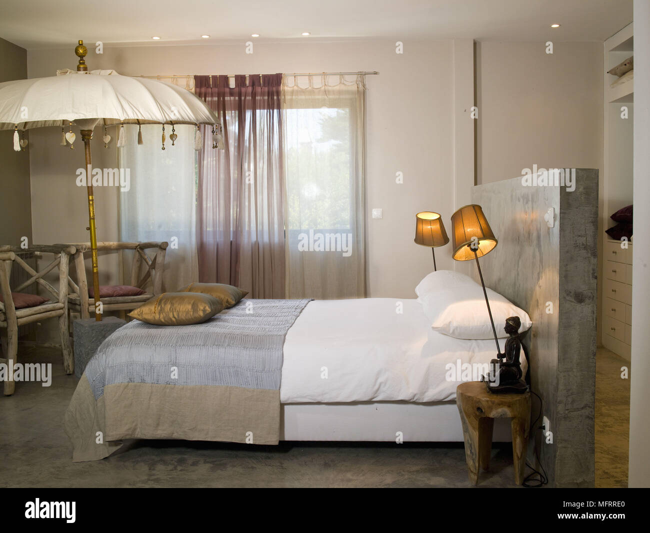 Accese le lampade al posto letto su tavoli laterali su entrambi i lati del letto matrimoniale Foto Stock