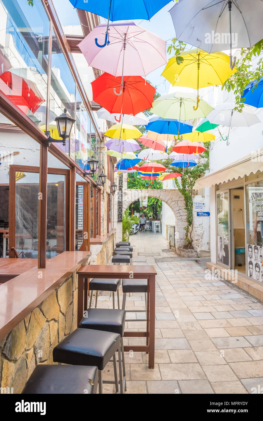 Ombrelloni colorati che pendono a strette strade di Bodrum con case bianche in stile greco Bodrum.Turchia.23 Agosto 2017 Foto Stock