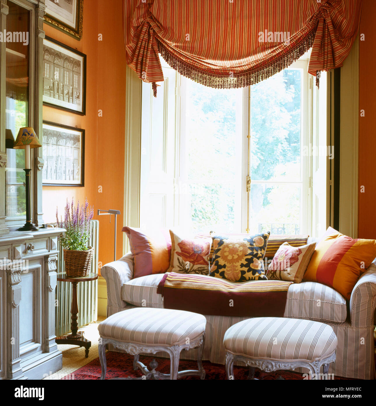 Un colore giallo tradizionale salotto con swag tende divani imbottiti e sgabelli cuscini Foto Stock