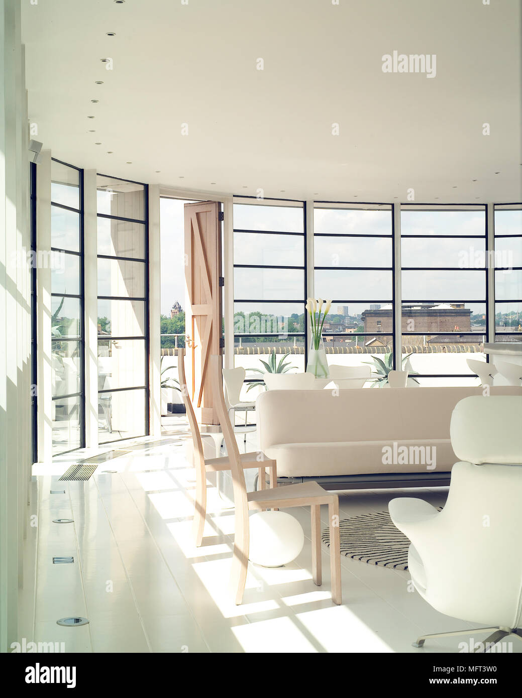 Un ultra moderno minimalista la stanza di seduta con curvatura pareti di vetro rivestito divano e poltrone rug Foto Stock