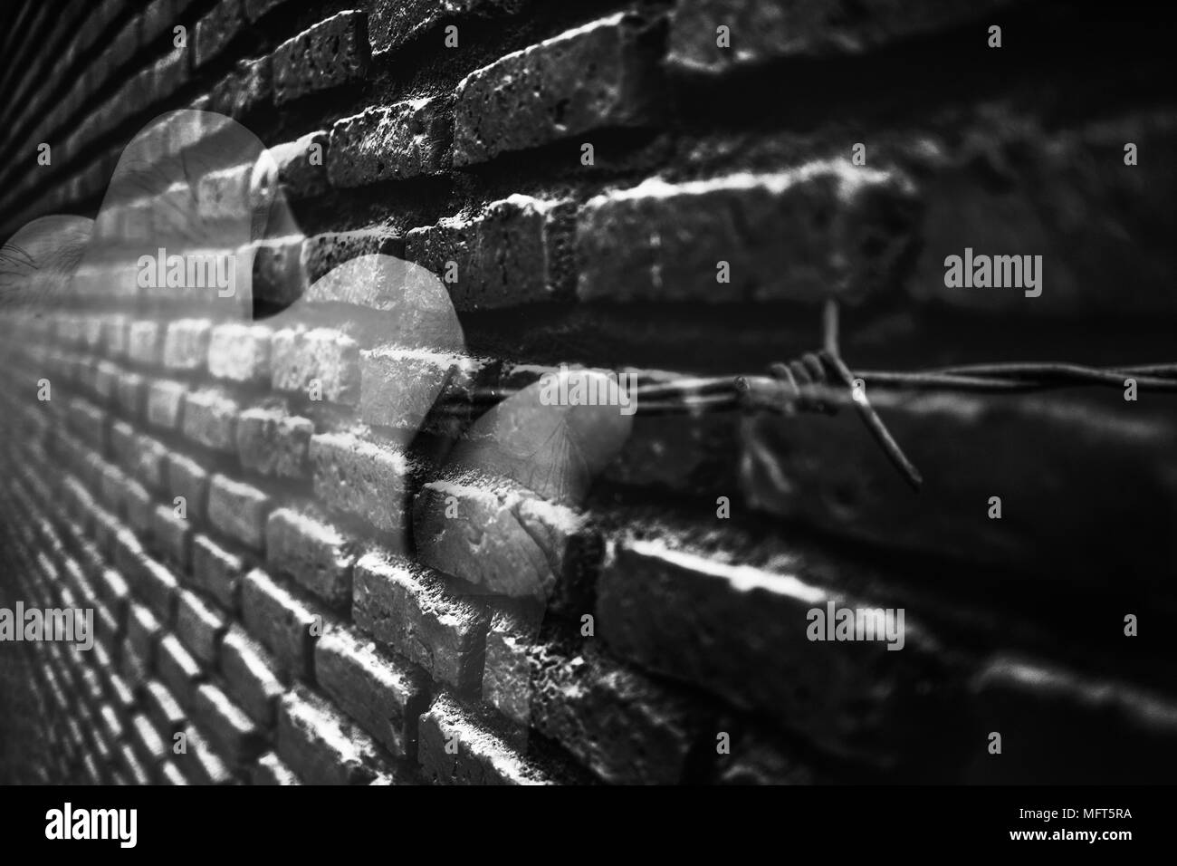 La doppia esposizione concetto del prigioniero mano sul filo spinato con un enorme muro di mattoni del carcere o prigione, mostrato nostalgia e attesa per la libertà nel bl Foto Stock