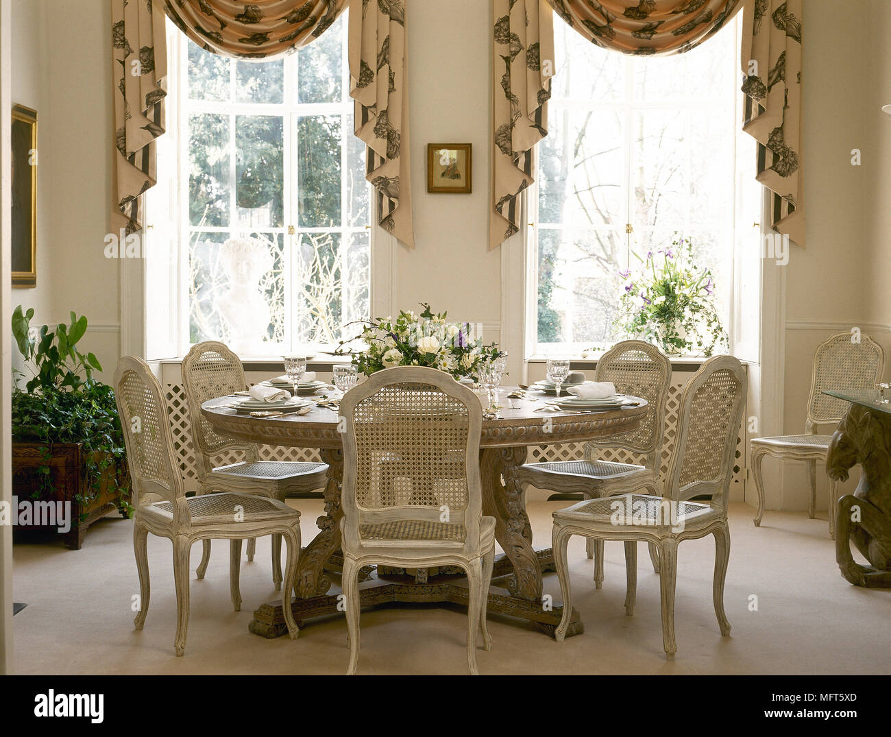 Un tradizionale, folle sala da pranzo con tavolo rotondo, dipinta periodo  sedie, swag tende Foto stock - Alamy