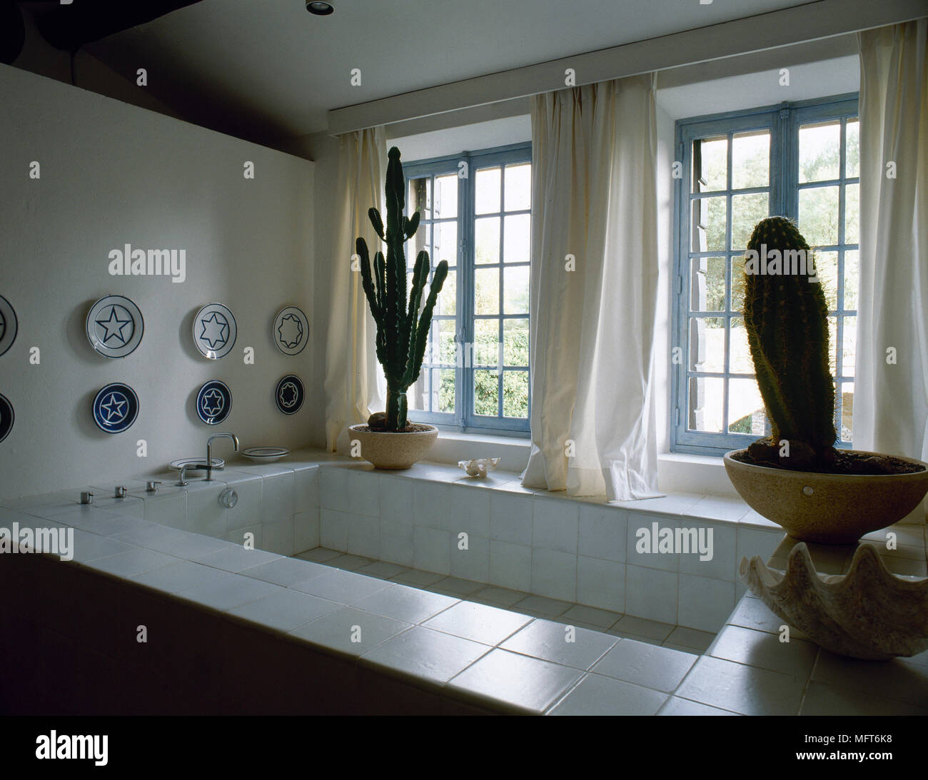 Bagno moderno dettaglio di una vasca da bagno profonda con piastrelle  surround, finestre con tende e vasi di cactus Foto stock - Alamy