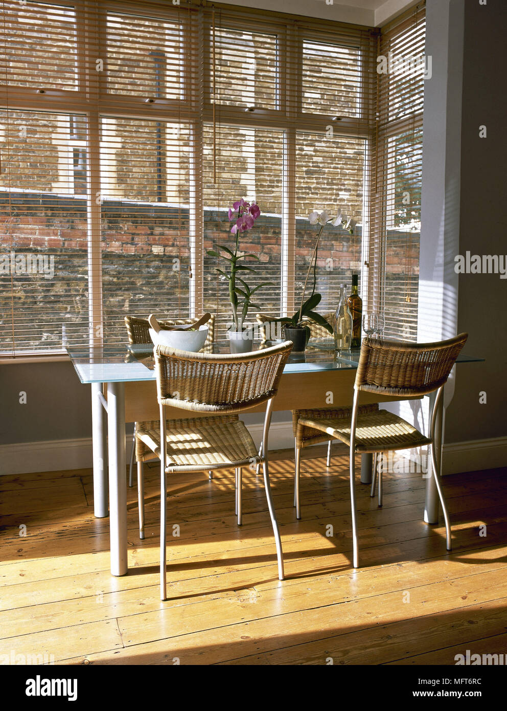 Moderna cucina sala da pranzo pavimento in legno tavolo in metallo tessuto sedie di vimini veneziane interni camere square finestre a baia naturale di folle compagno di colori Foto Stock
