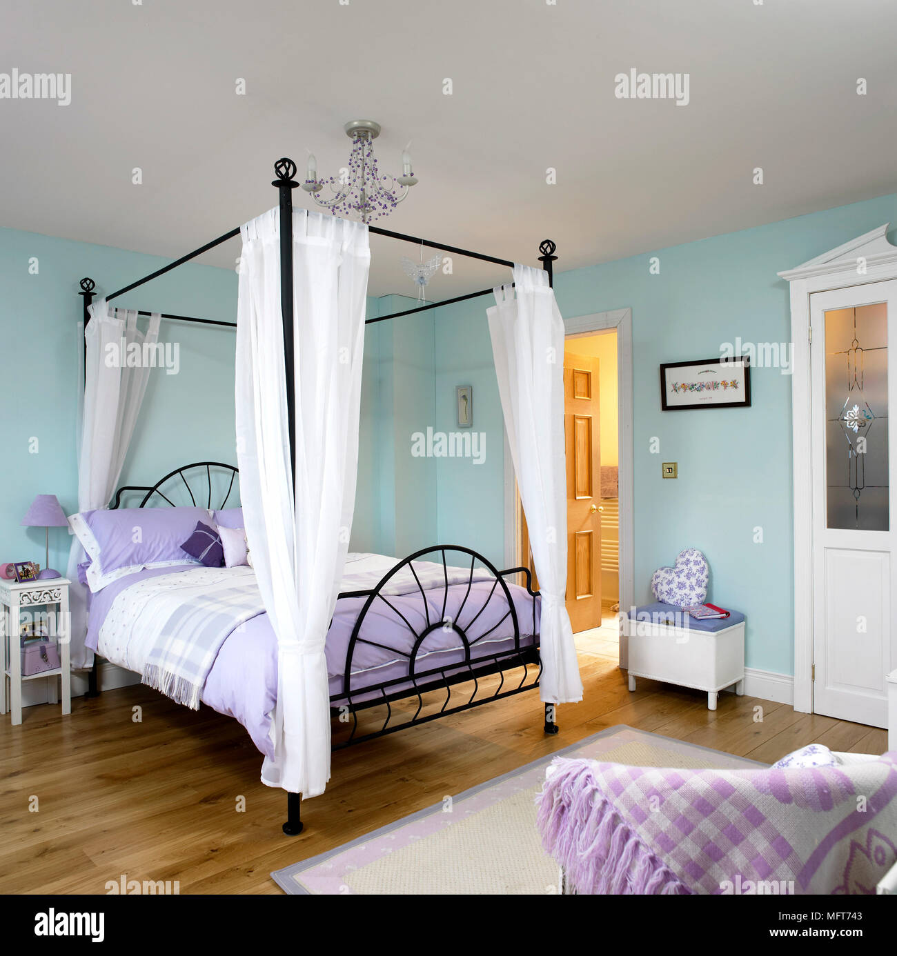 Un tradizionale blu pallido in camera da letto, letti in ferro battuto con baldacchino  letto doppio con teli di tessuto, comodino, lampada, lampadario, pavimento  in legno, tappeto Foto stock - Alamy