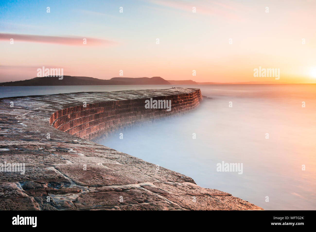 Sunrise oltre il Cobb a Lyme Regis nel Dorset. Foto Stock