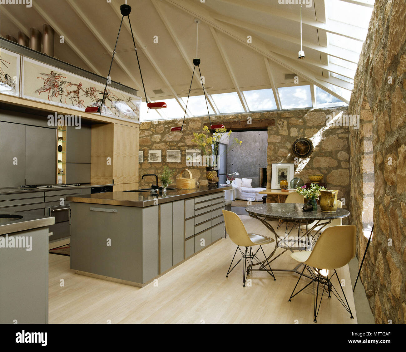 Moderna cucina a pianta aperta e zona pranzo con isola centrale unità e pareti in pietra esposta Foto Stock