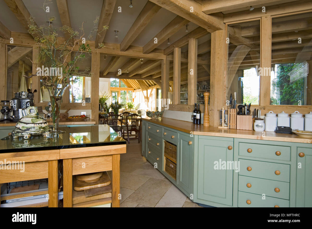 Cucina con tavolo e piani in legno sotto travi di legno esposte Foto Stock